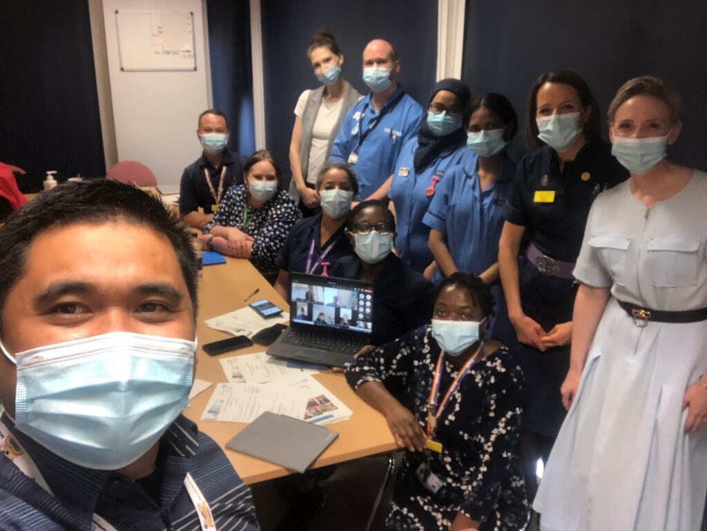 A selfie image of people standing around a table wearing face masks.