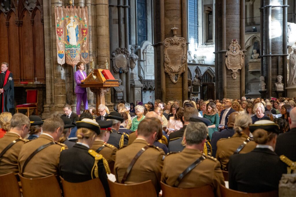 A woman in a purple suit speaking to the congregation in Westminster Abbey