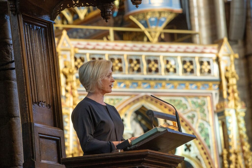 A side view of a woman standing at a lectern in Westminster Abbey speaking.