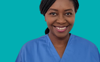 A headshot of a woman smiling, she has black hair which is tied back and she is wearing a nursing uniform top.