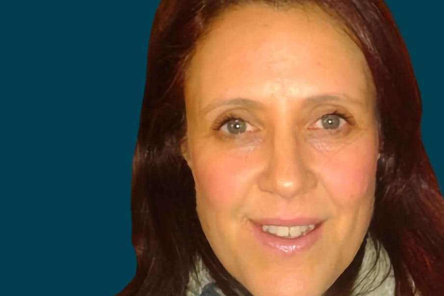 Close up headshot of a woman who has dark brown hair, and is smiling.