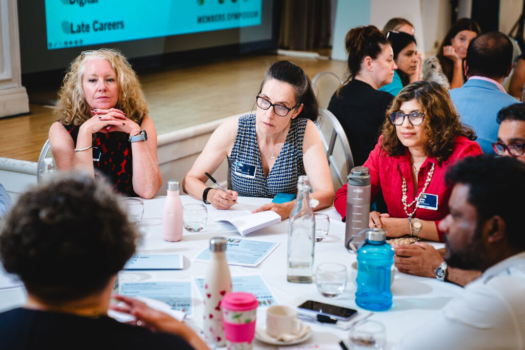 A group of people sitting round a table listening to each other speak.