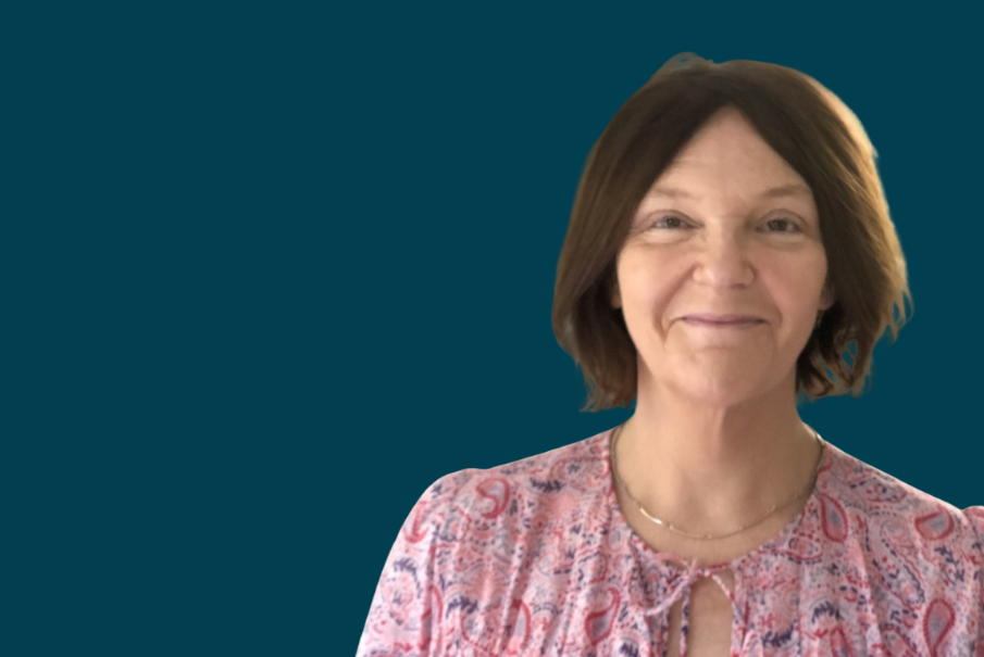 A head and shoulders image of a woman with chin length brown hair. She is smiling and wearing a floral blouse.