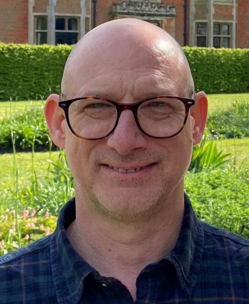 Headshot of a man in glasses smiling.