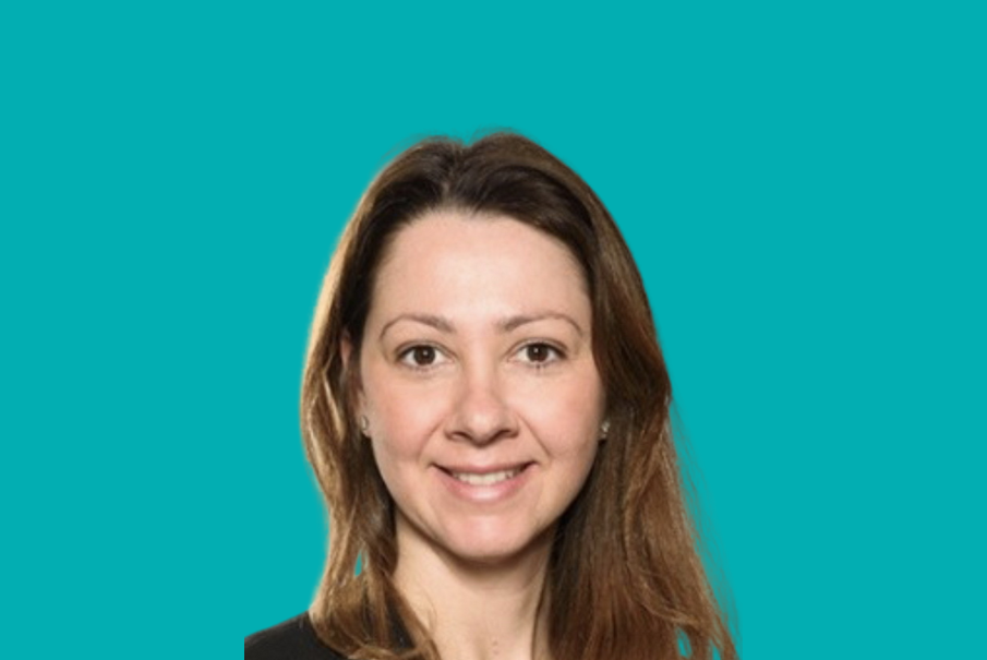 Headshot of a woman with long brown hair, she is smiling.