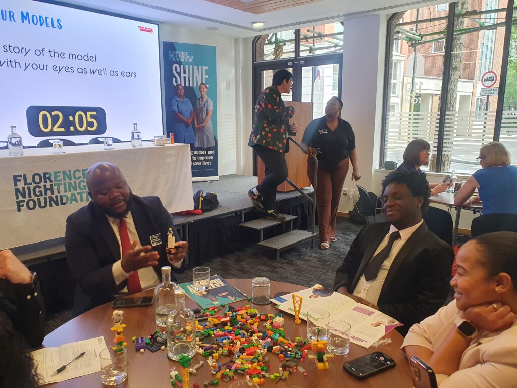 A group of people sitting around a table with lots of lego pieces on it.