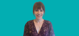 Head and shoulders image of a woman with light brown hair, she is wearing a patterned top and is smiling.