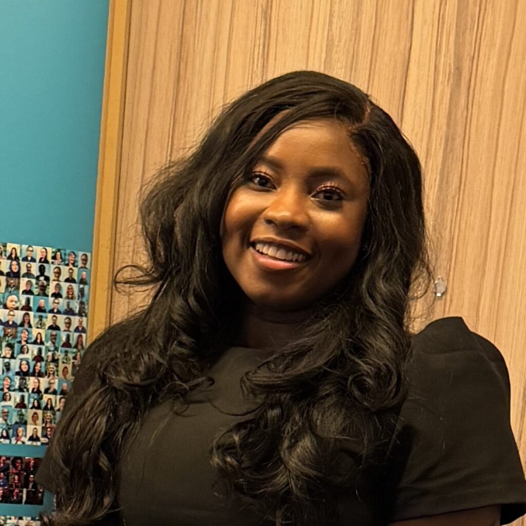 Image of a woman with long black hair, she is wearing a black dress and is smiling.