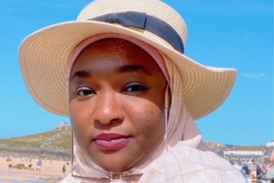 A close up image of a woman wearing a hat with a blue sky in the background.