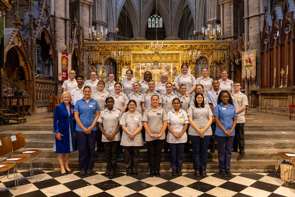 A large group of students in nursing uniform from Anglia Ruskin University. Standing in a group smiling at the camera.