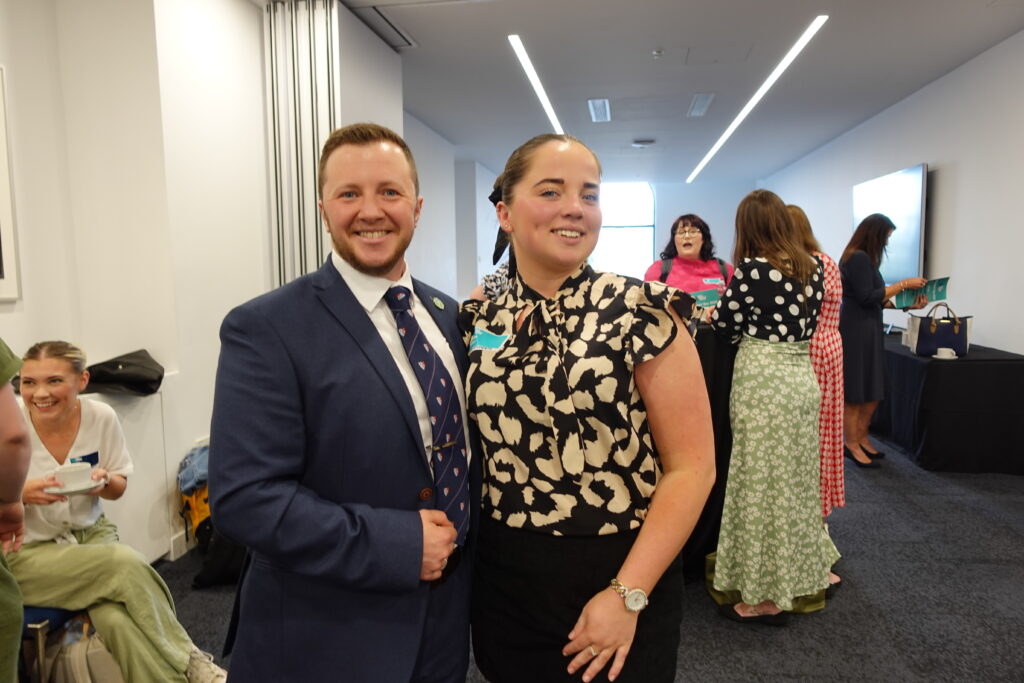 A man and woman stading together in a foyer area smiling at the camera
