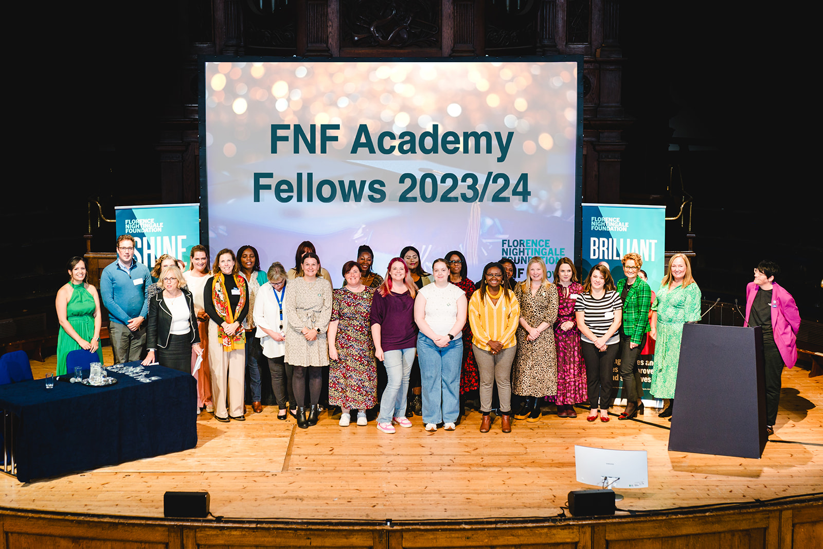Group of people on a stage with a screen behind saying FNF Acedemy Fellows 2023/24.