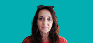 A head and shoulders image of a woman with long dark hair in an red/orange top. She has sunglasses on the top of her head and there is a teal coloured background to the image.