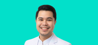 Head and shoulders image of a man smiling. He has short dark hair and is wearing a light jacket and shirt.