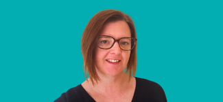 Head and shoulders image of a woman with shoulder length brown hair. She is wearing a black top and is wearing a pair of glasses and she is smiling.